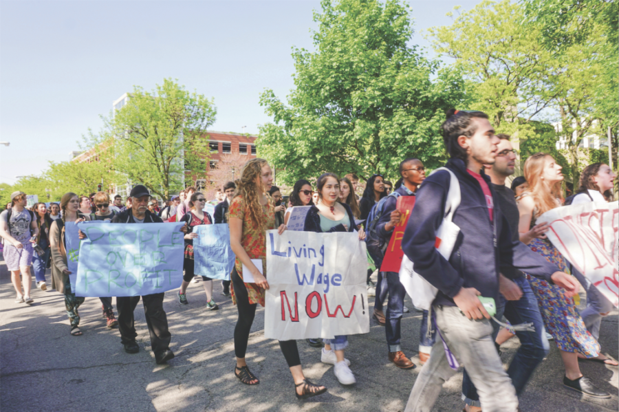 Students walk down the street during the protest to democratize the University holding various posters.