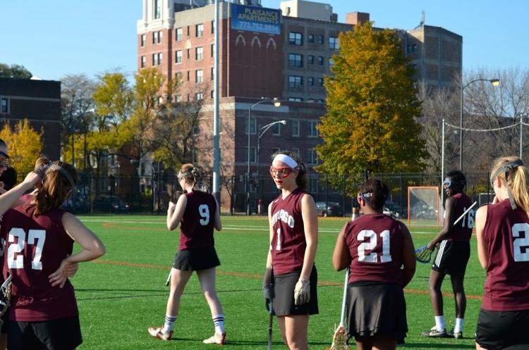 The womens club lacrosse team stands on the field.