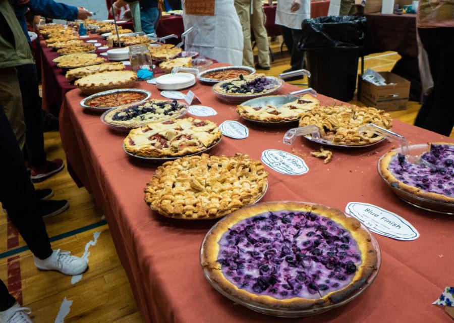 Dozens of fruit pies line the table, sliced and ready for eating