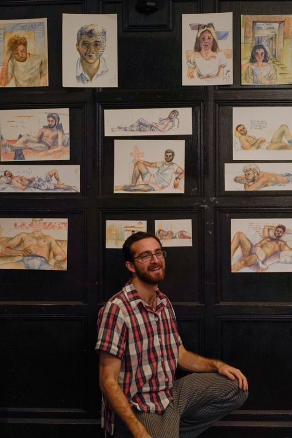 Kaan Tarhan stands poses in front of his series of portraits, titled Chat & Sketch.