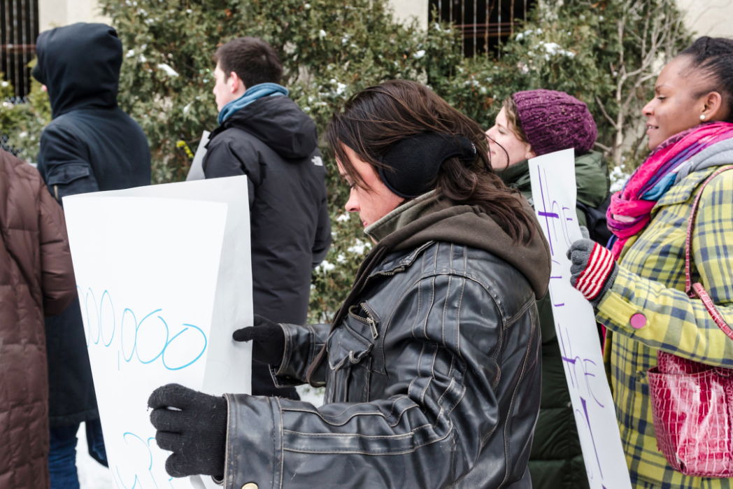 Detective Marcellis marches with the protesters from 61st and Cottage Grove to President Zimmer's house, holding a sign reading, 