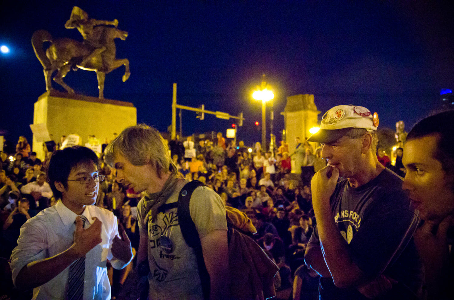 Fourth-yearKelvin Ho (left) speaks with fellow leaders before the start of the Occupy Chicago group's daily General Assembly Monday evening along Michigan Avenue.