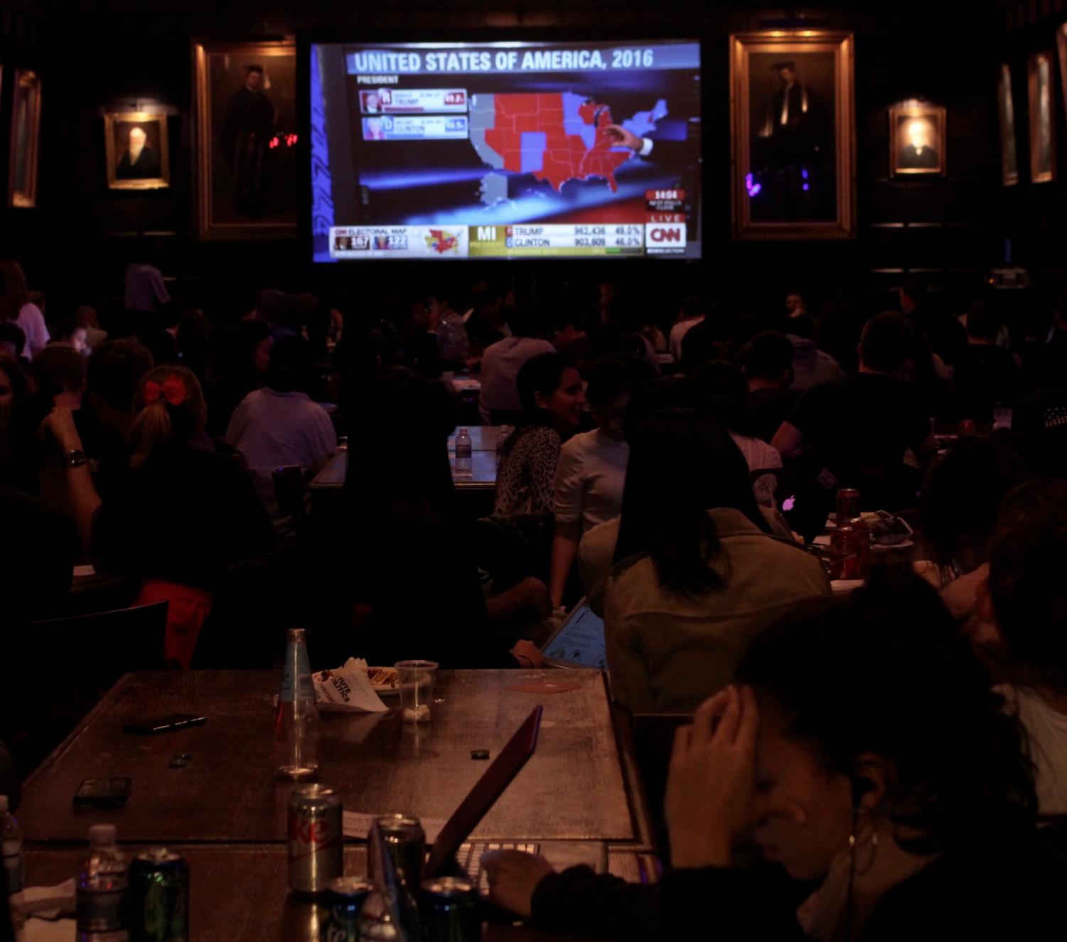 A woman leans her head in her hands at the Institute of Politics watch party.