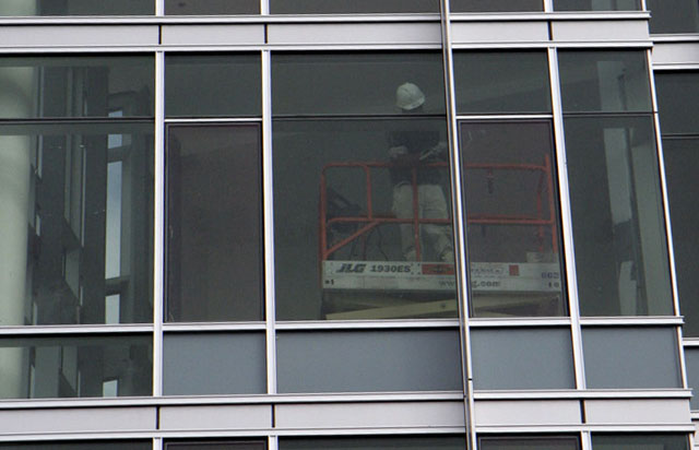 A construction worker inside the new dormitory works on a window on the building's west side.