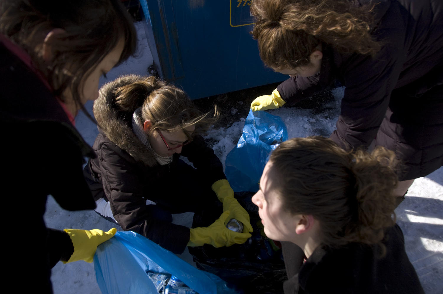 Nathalie Lowenthal-Savy (bottom-right), Tiffany Sommadossi (left), Molly FitzMaurice (right) and Sarah Rodriguez (center) reach inside trash bags searching for recyclable material.