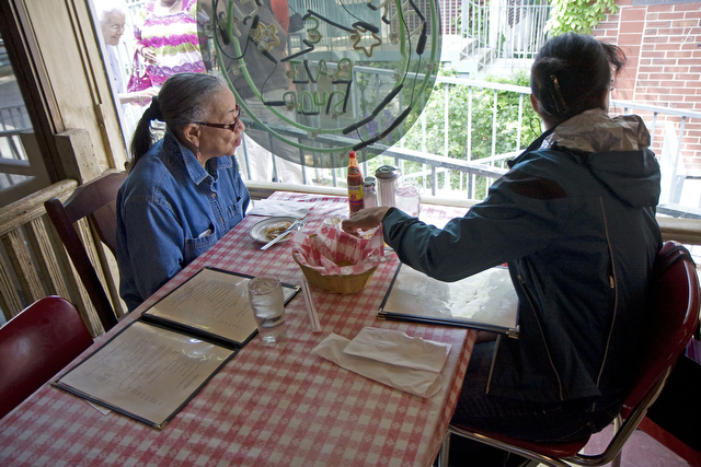 Dorothy Wright (left) and Celeste Harris (right), residents of Bronzeville, enjoy johnny cakes while waiting for their meal.