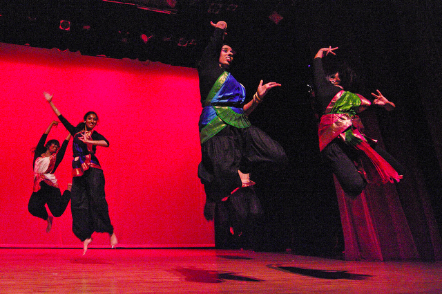 Dancers leap off the stage floor during a traditional dance.