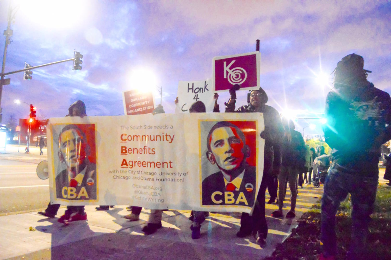 Protesters from the Obama Library South Side CBA Coalition hold signs on their march to Jackson Park.