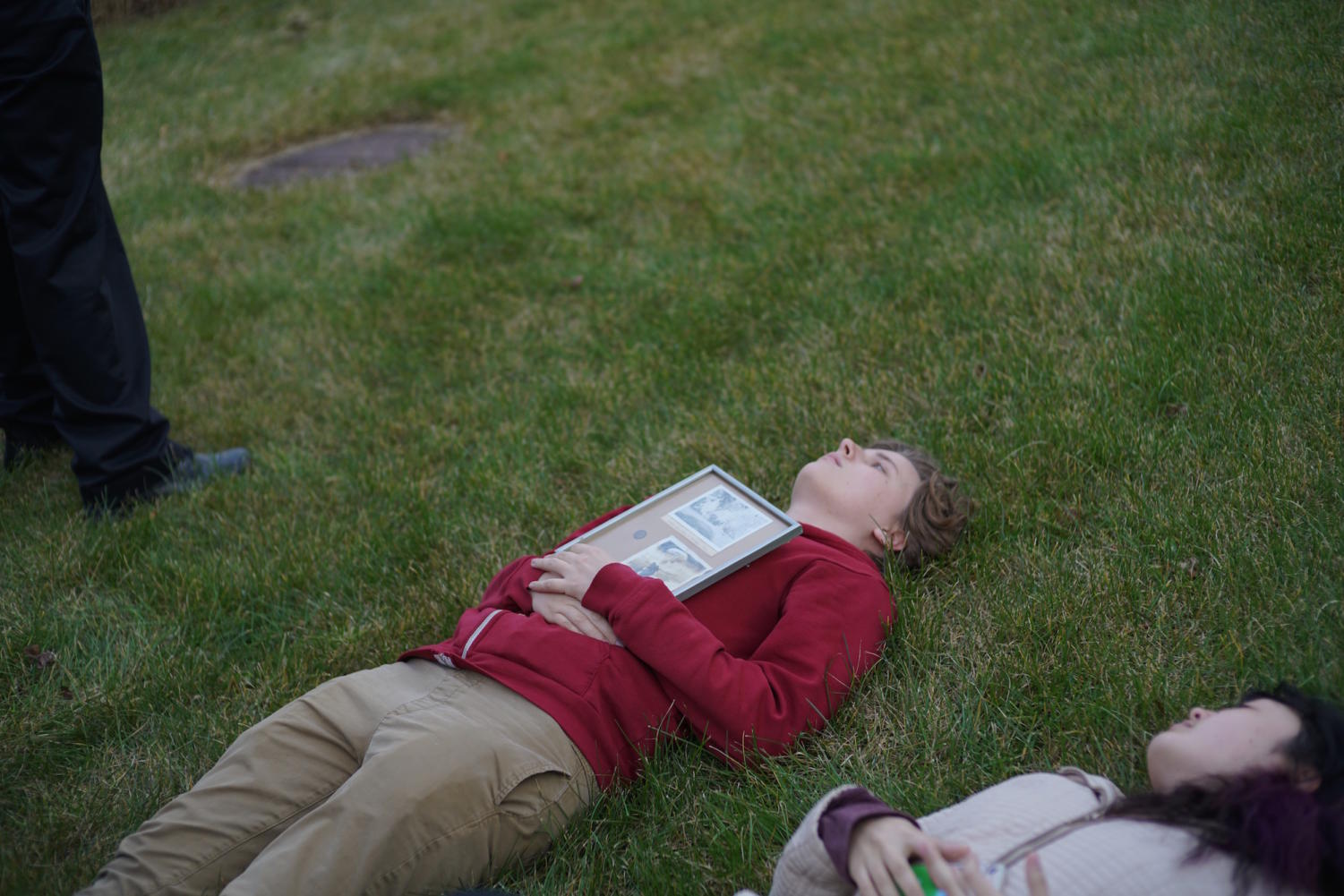 Fourth-year Athena Kern and second-year Jay Hoshina lie on the grass during the artwork. Kern held a collage of pictures of Eckhart Hall and the bombing of Nagasaki put together by her grandfather, who once worked on the bomb at the University.