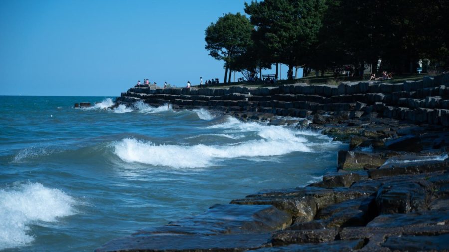 Promontory Points limestone seawall faces a summer wave on a day with a clear sky.
