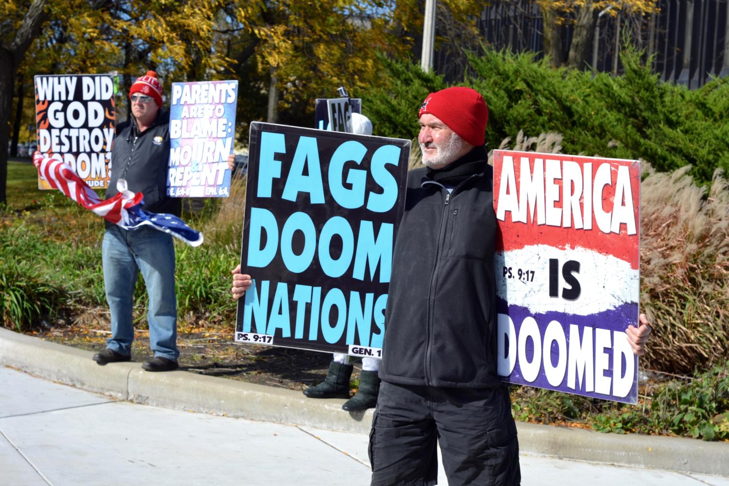 A Westboro Church picketer holds signs reading 