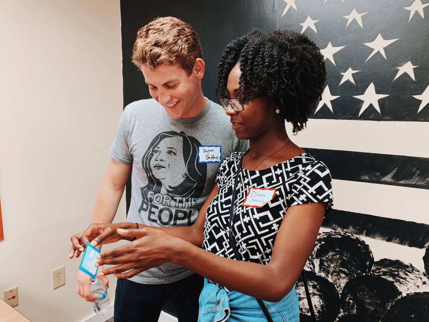 Dylan Stafford ‘20 and Dinah Clottey ‘22 watch as a polaroid photograph develops at the opening for Kamala Harris’ Des Moines field office.