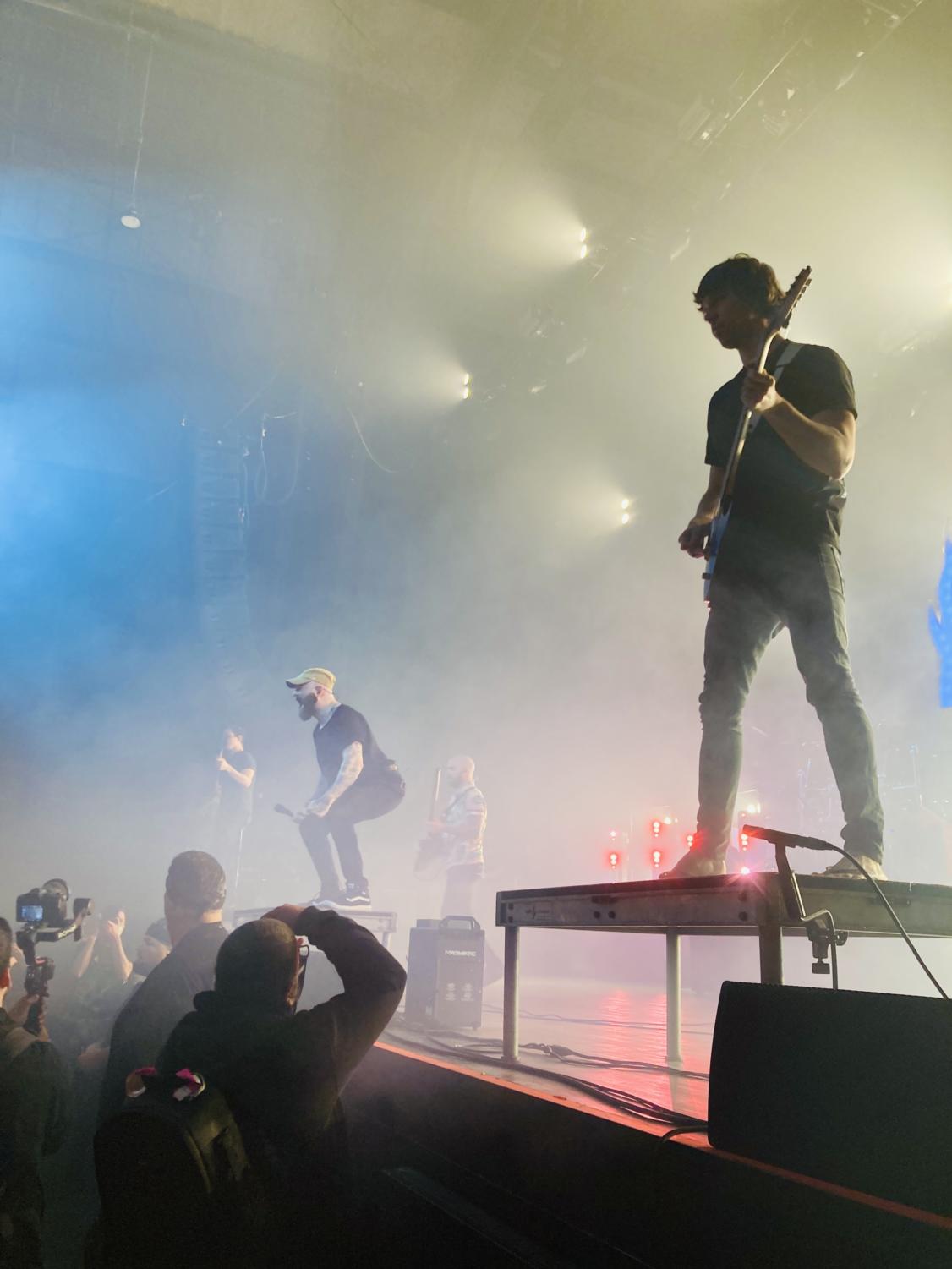 Journalists photograph opening band August Burns Red through smoke.