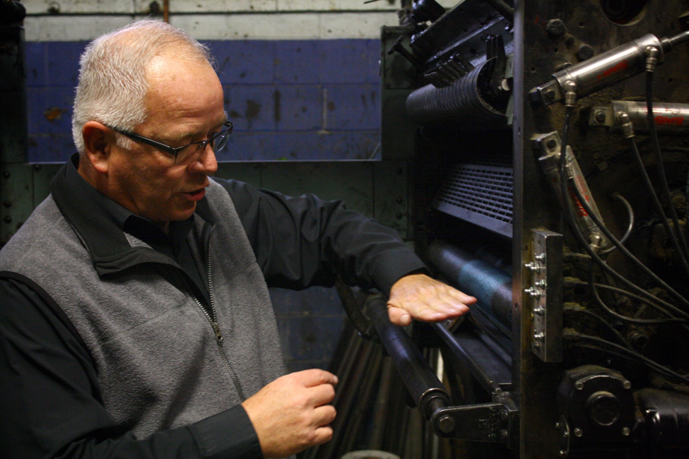 Gouwens demonstrates the process of offset printing. After PDFs of the pages are received, the text and images are exposed onto a metal plate and developed with chemicals. The plate wraps around the cylinder and ink is brought down from the rollers.