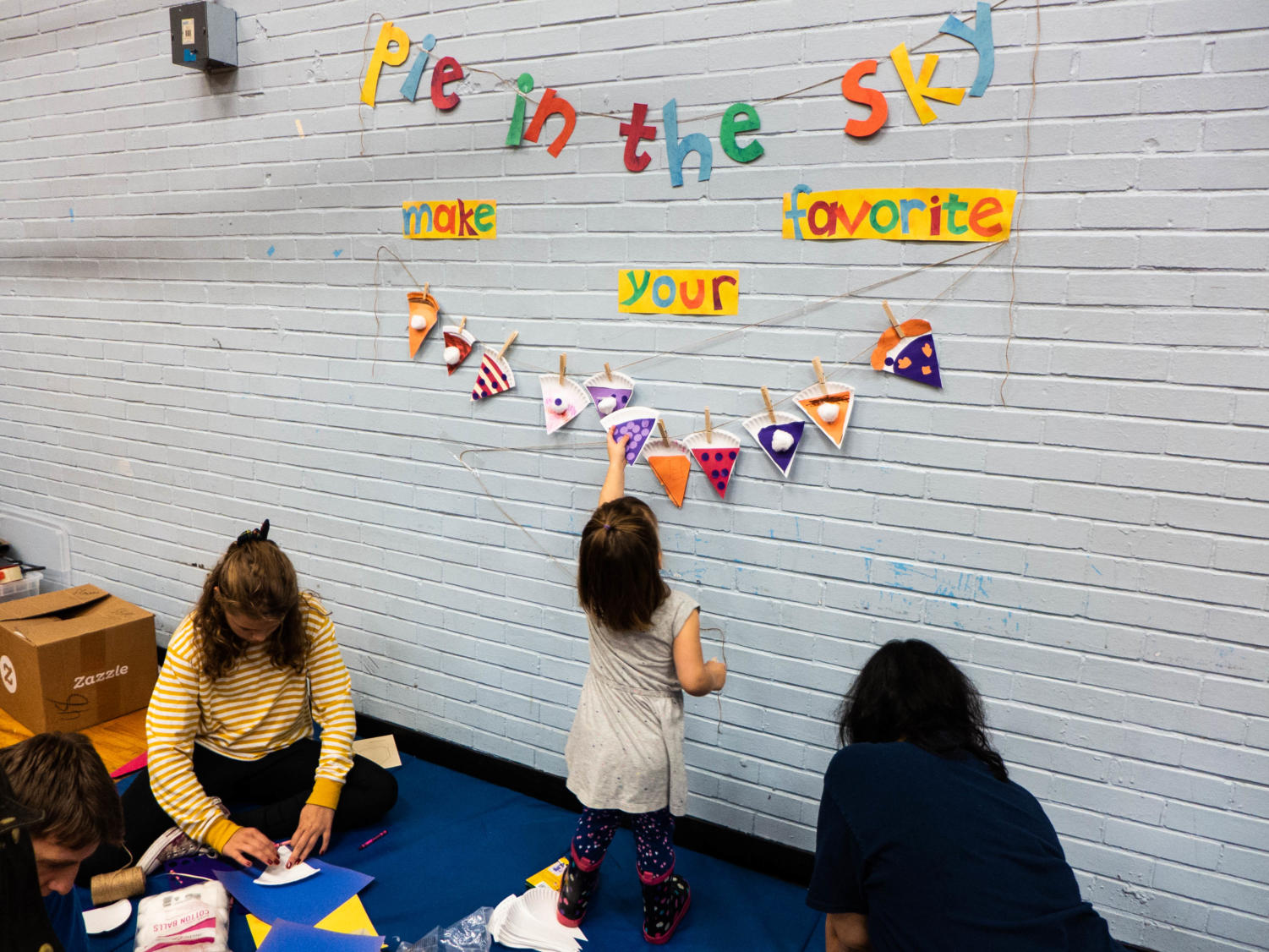 A child hangs up a pie-themed craft, at the event’s kid station.