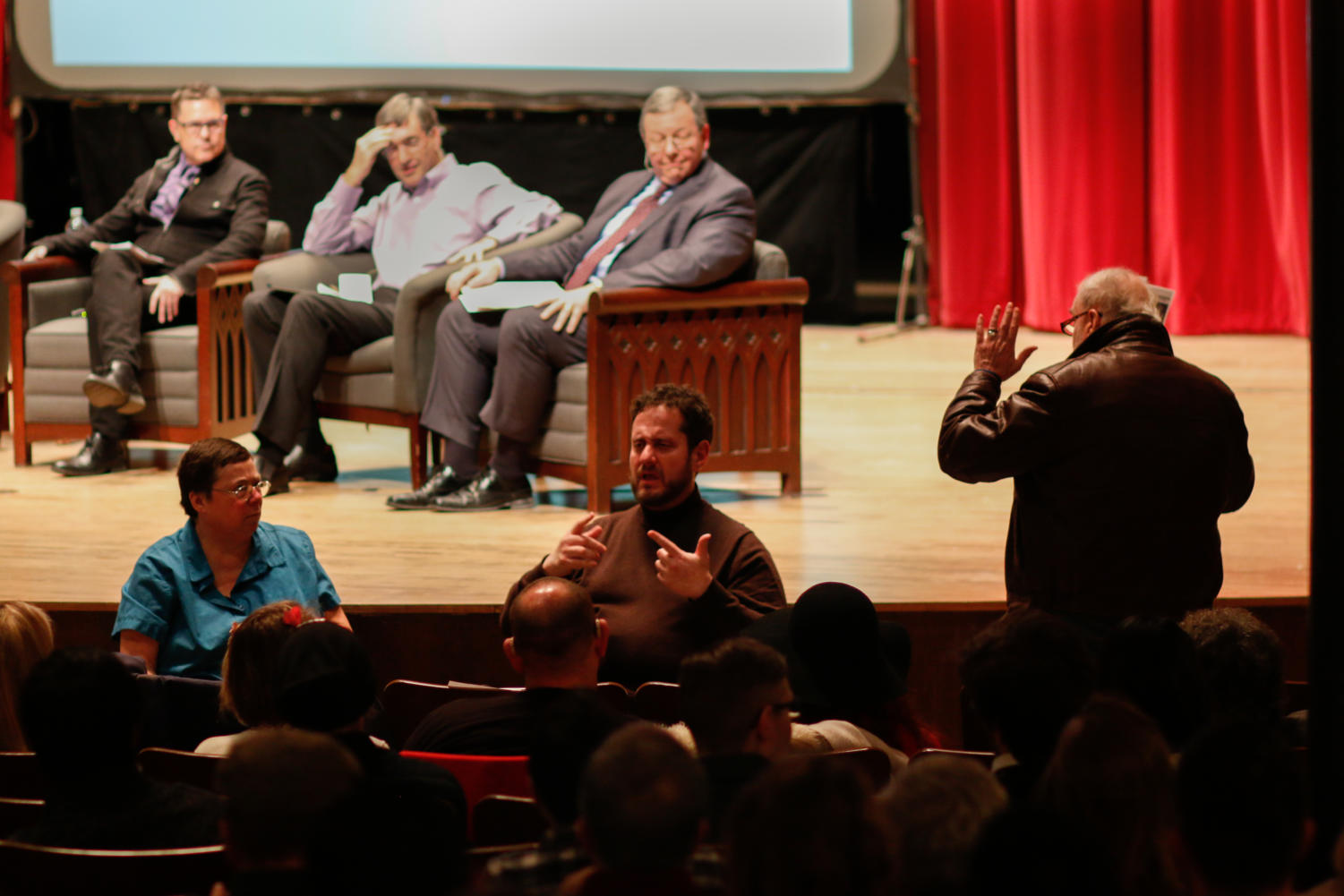 An audience member interrupts the panel discussion. After being chided by the moderator, he sits down.
