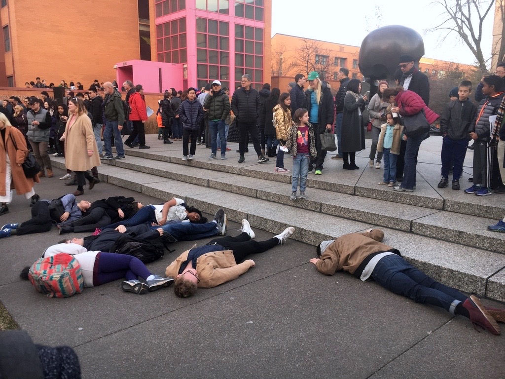 Students lie silently by Henry Moore's Nuclear Energy sculpture as a flash performance, 