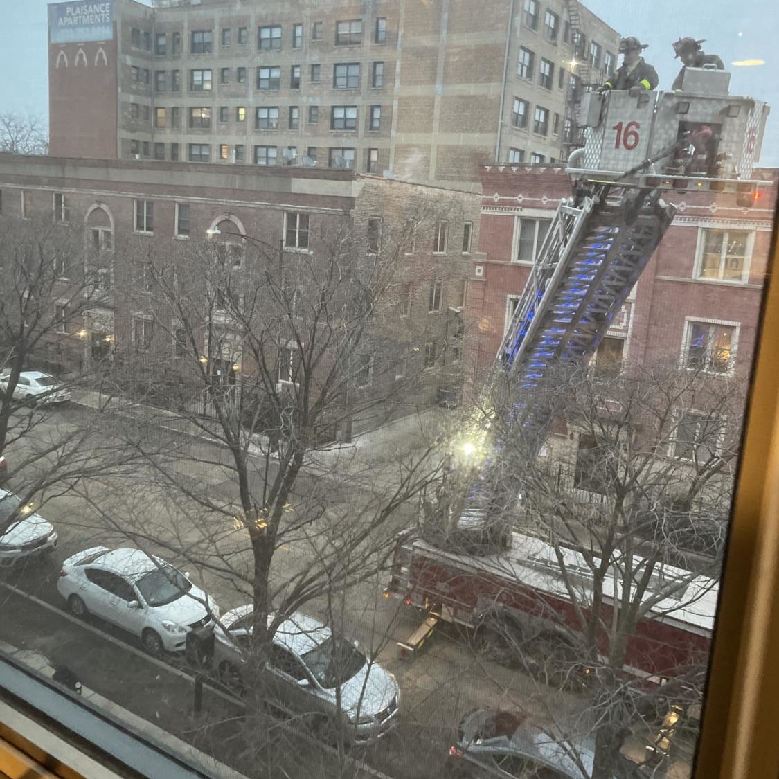 A view of a fire truck, with the ladder extended upward, on East 61st Street from a room in Woodlawn Residential Commons