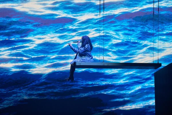 SZA sits at the edge of a suspended platform at her United Center performance. 