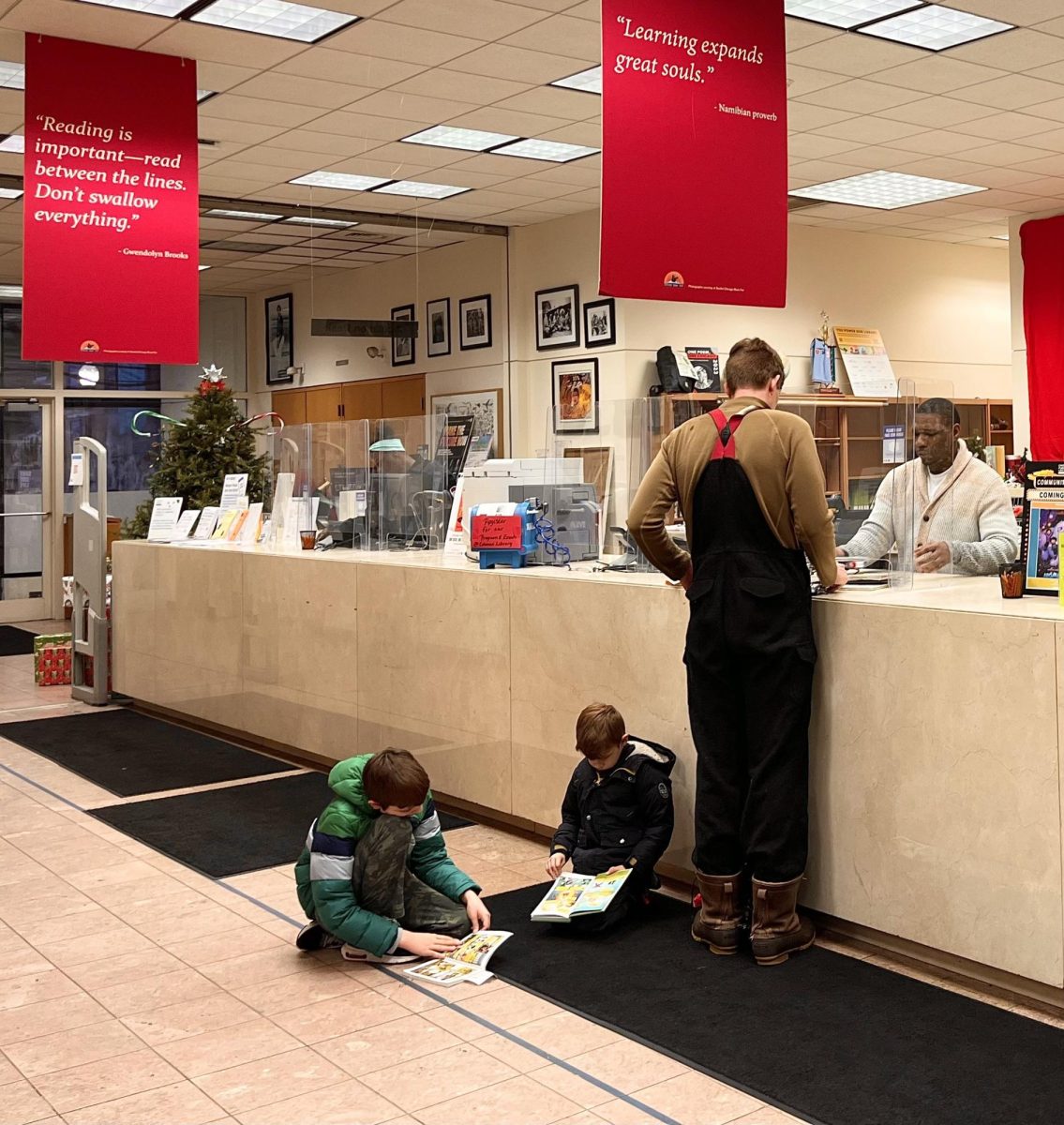 A librarian helping a visitor at the front desk of the Coleman branch.