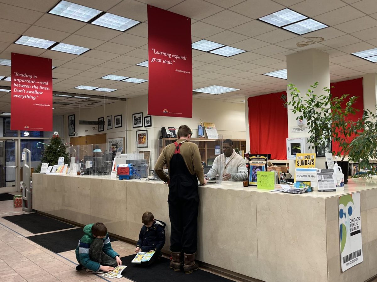 A librarian helping a visitor at the front desk of the Coleman branch.
