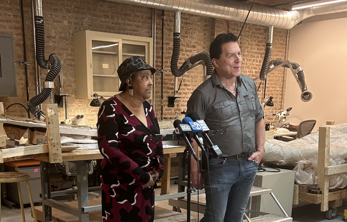 Professor Paul Sereno and Washington Park Advisory Council Representative Cecilia Butler stand in the fossil preparation room, speaking about the creation of the fossil lab.
