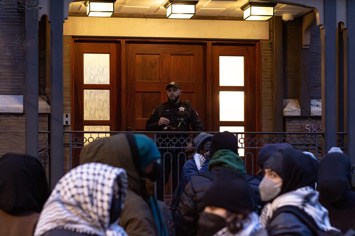  A UCPD officer stands on the steps of University President Paul Alivisatos’s house while protesters rallied outside.