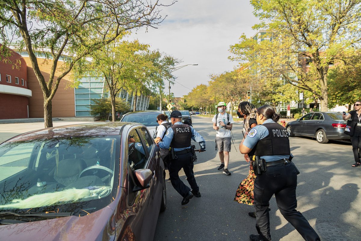 From the October 11 UCUP protest: The student in the orange skirt was arrested on December 11 and charged with “aggravated battery of a peace officer” and “causing an injury while resisting or obstructing a peace officer.” They were allegedly attempting to prevent the arrest of the student in khaki shorts, who was charged with “aggravated battery of a peace officer.”