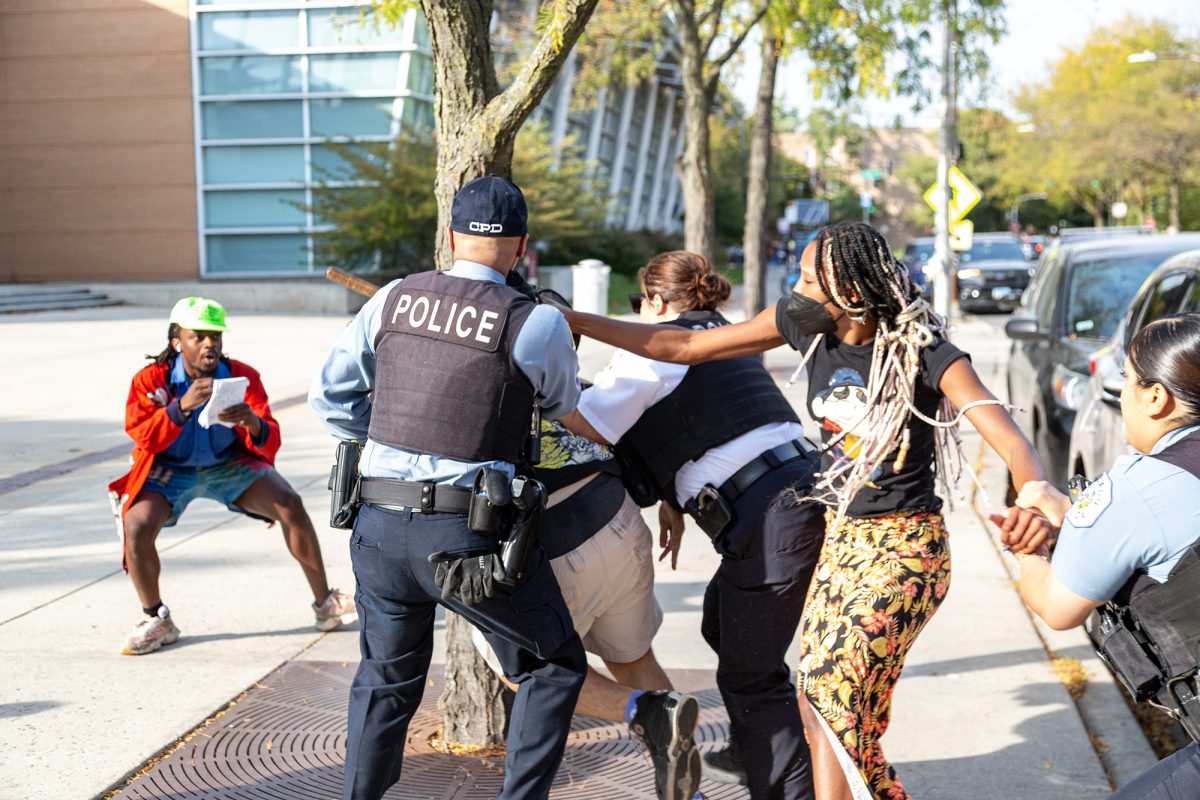 From the October 11 UCUP protest: The student in the orange skirt was arrested on December 11 and charged with “aggravated battery of a peace officer” and “causing an injury while resisting or obstructing a peace officer.” She was allegedly attempting to prevent the arrest of the student in khaki shorts, who was charged with “aggravated battery of a peace officer.”