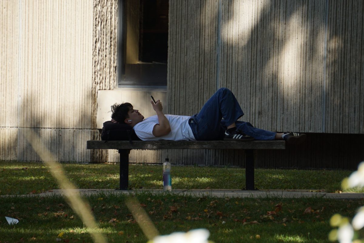 A student relaxes on a bench in front of Joseph Regenstein Library.