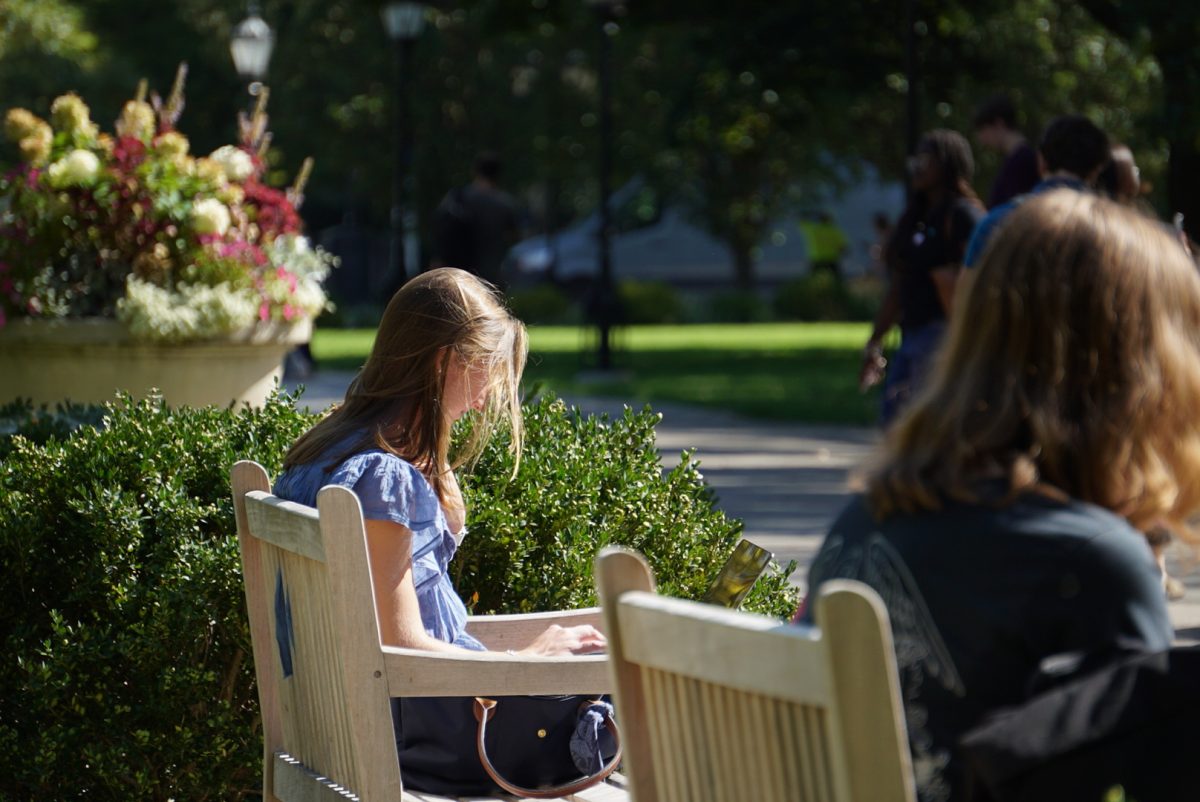 A student works on one of the benches in the middle of the main quad.
